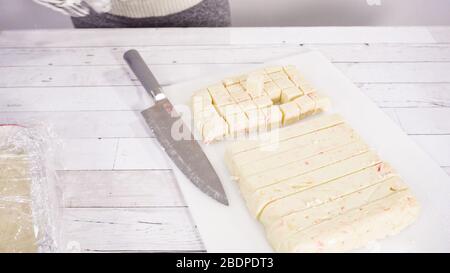 Étape par étape. Coupe de fudge de canne à sucre fait maison sur un tableau de découpe blanc. Banque D'Images