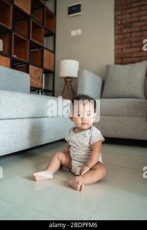 portrait de bébé assis sur le sol à la maison Banque D'Images