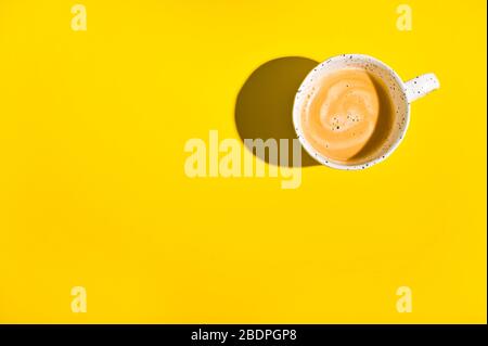 Tasse boisson chaude café dispersé sur fond jaune vue sur le dessus plat. Photo avec lumière dure. Beaucoup d'espace libre pour le texte. Ci-dessus . Banque D'Images