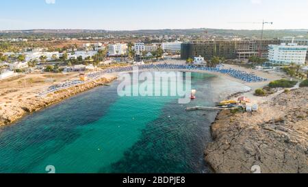 Vue panoramique sur la plage de Vathia Gonia, Ayia Napa, Famagusta, Chypre. L'attraction touristique historique baie rocheuse au lever du soleil avec sable doré, soleil Banque D'Images