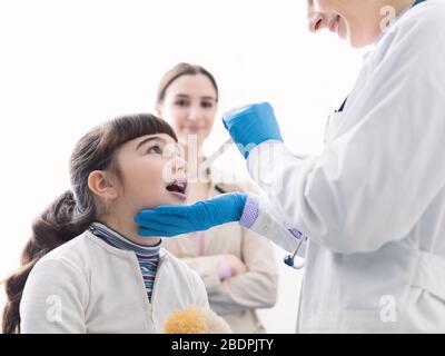 Médecin professionnel vérifiant la gorge d'une fille, elle ouvre la bouche Banque D'Images