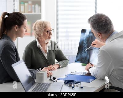 Médecin vérifiant l'image radiographique d'une patiente âgée au cours d'une visite à l'hôpital, concept de blessure et d'ostéoporose Banque D'Images