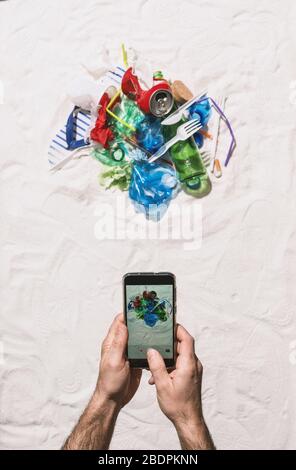 Homme prenant une photo de la pollution des déchets sur la plage et la partager en ligne à l'aide de son smartphone, protection de l'environnement et pollution plastique conceps Banque D'Images