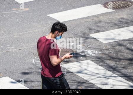 La Nouvelle-Orléans, LA/USA - 4/5/2020: Man Crossing Street avec masque et téléphone portable Banque D'Images
