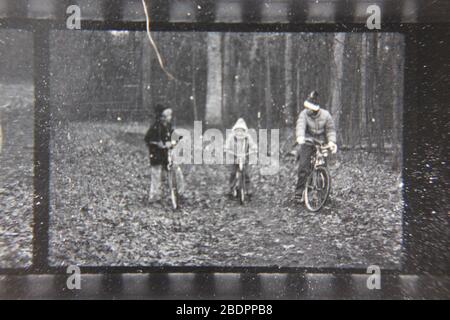 Belle photographie en noir et blanc vintage des années 1970 des enfants qui font du vélo dans les bois. Banque D'Images