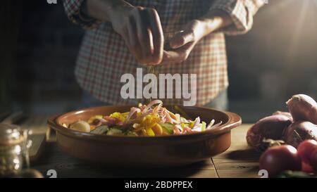 Femme préparant un repas sain à la maison, elle assaise des légumes mélangés dans un coup Banque D'Images