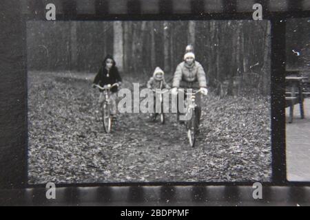 Belle photographie en noir et blanc vintage des années 1970 des enfants qui font du vélo dans les bois. Banque D'Images