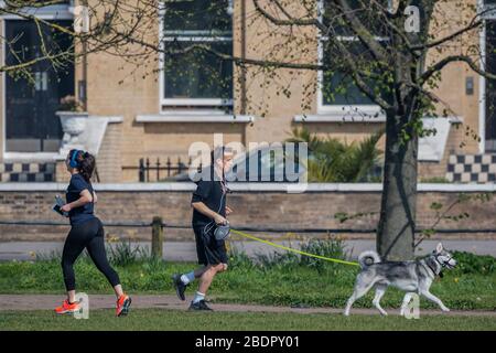 Londres, Royaume-Uni. 9 avril 2020. Courir avec leur chien - Clapham Common est assez calme maintenant Lambeth Conseil a enregistré tous les bancs. Le « verrouillage » se poursuit pour l'épidémie de Coronavirus (Covid 19) à Londres. Crédit: Guy Bell/Alay Live News Banque D'Images