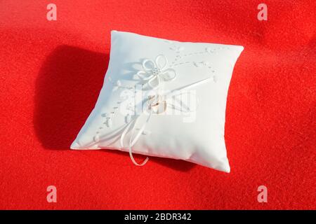 Coussin avec deux anneaux de mariage dorés sur fond rouge Banque D'Images