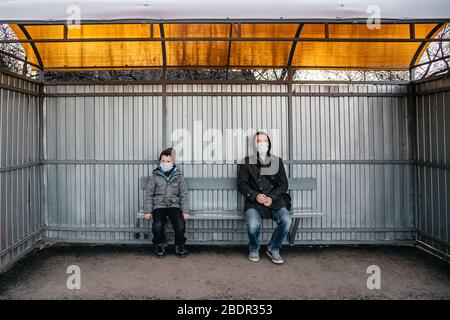 La distance sociale de 1 mètre entre un homme et un enfant est assise à un arrêt d'autobus en raison de la pandémie Covid 19. Protection sociale contre le Banque D'Images