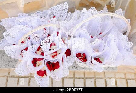 Des cônes de papier blanc aux pétales de rose placés dans deux paniers pour une célébration Banque D'Images