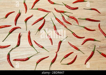 fond - les gousses de piment rouge se répandent uniformément sur une surface en bois Banque D'Images