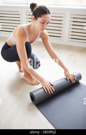 Jeune femme sportive préparant son tapis d'exercice pour l'entraînement sportif dans la classe Banque D'Images