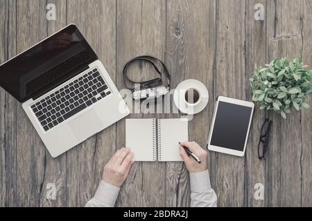 Auteur créatif indépendant, photographe et journaliste travaillant au bureau, il écrit des notes sur un ordinateur portable, vue de dessus Banque D'Images