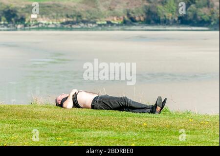 Inchydoney, West Cork, Irlande. 9 avril 2020. Un homme profite de l'occasion pour faire un bain de soleil près d'une plage déserte d'Inchydoney aujourd'hui pendant le verrouillage de Covid-19. Crédit : Andy Gibson/Alay Live News Banque D'Images