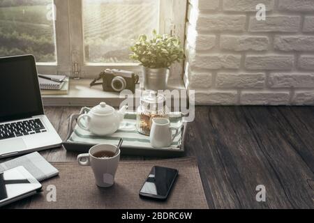 Petit déjeuner sain et relaxant à la maison sur une table en bois rustique avec ordinateur portable et smartphone Banque D'Images