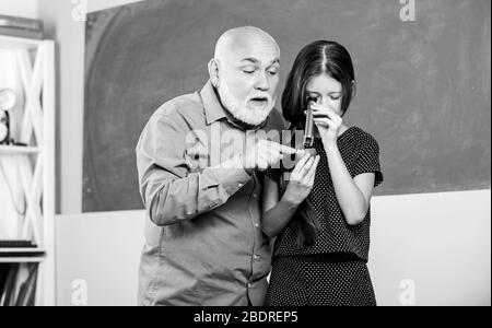 Sagesse. Professeur mûr regarder à travers la loupe tube sur la chaux. Petite fille explorer la tranche de fruits. École. Microscopie. Analyse et synthèse. Élargir la connaissance du monde. Échantillon biologique. Banque D'Images