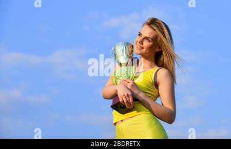 Prix Gold. Un athlète mignon récompensé par une tasse. Prix de la première place et succès. Fille a un trophée d'or. Femme a remporté le concours. Prix de la femme gagnant. Heureuse fille a remporté le trophée. Succès sportif. Banque D'Images