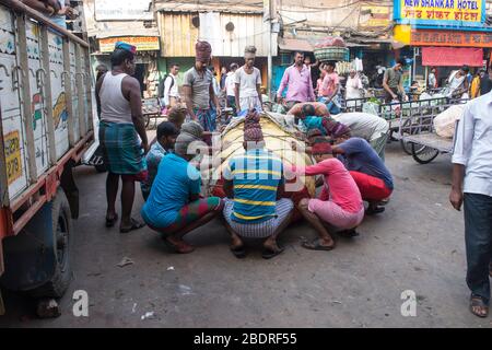 Travailleur préparant la prise d'une lourde charge de marchandises dans le marché de Koley, Kolkata, Inde. Banque D'Images