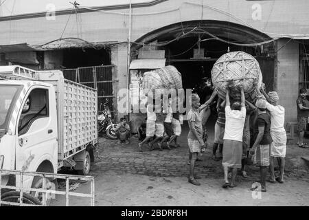 Les travailleurs qui ramassent une lourde charge de marchandises dans le marché de Koley, Kolkata, Inde. Banque D'Images