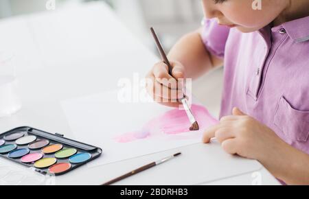 Jolie fille heureuse peinture avec aquarelles sur une feuille, l'éducation et la créativité concept Banque D'Images