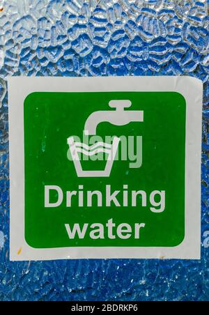 Panneau d'eau potable avec texte blanc et symbole robinet et symbole verre sur fond vert sur fenêtre de verre. Banque D'Images