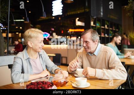 Couple d'âge mûr profitant de la tasse de thé et de parler les uns avec les autres tout en ayant une date dans le café Banque D'Images