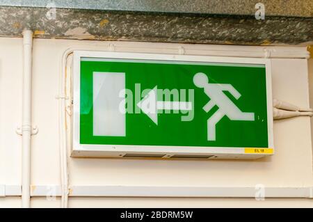 Une plaque de signalisation de sortie verte au néon avec un personnage désactivé, un personnage homme et une flèche vers la porte comme instructions pour les directions en cas d'urgence Banque D'Images