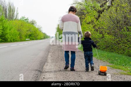 L'enfant avec sa mère marchant le long de la route. Banque D'Images