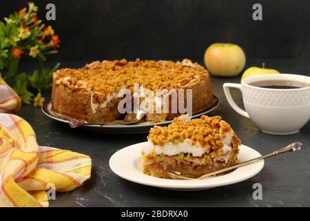 Gâteau avec pommes, meringues et tasse de thé est situé sur une plaque sur un fond sombre Banque D'Images