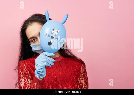 Femme en gants médicaux et masque chirurgical tenant le mignon lapin de Pâques. Femme célébrant Pâques 2020 en quarantaine pendant le covid-19 Banque D'Images