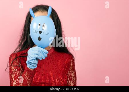 Femme en gants médicaux et masque chirurgical tenant le mignon lapin de Pâques. Femme célébrant Pâques 2020 en quarantaine pendant le covid-19 Banque D'Images