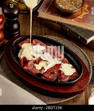 la crème est versée sur les tranches de viande crues cuites Banque D'Images