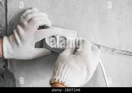 Travailler sur l'installation de prises électriques. L'assistant remplace l'ancienne sortie par une nouvelle. Espace de copie. Banque D'Images