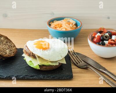 cheeseburger végétarien servi avec salade de tomates, olives et feta, salade de fenouil et carottes. Banque D'Images