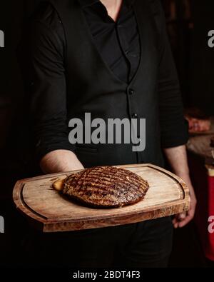 un serveur qui tient des steaks farcis au fromage est servi sur planche en bois Banque D'Images