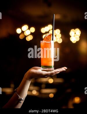 femme tenant main cocktail de pamplemousse avec paille noire Banque D'Images