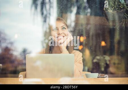 Rêvant de jour. Belle femme pensive avec tasse à café assis à côté de la fenêtre à la cafétéria Banque D'Images