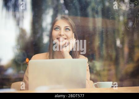 Rêvant de jour. Belle femme pensive avec tasse à café assis à côté de la fenêtre à la cafétéria Banque D'Images