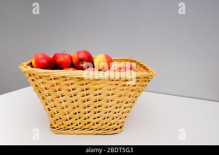 panier en osier avec pommes rouges, panier avec pommes sur table Banque D'Images