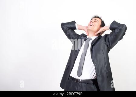 Homme détendu en costume se penchant en arrière avec ses mains sur le dos de son cou.. Fond blanc, prise de vue moyenne Banque D'Images