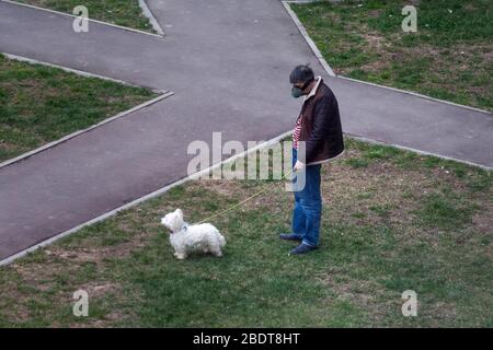 Moscou, Russie. 8 avril 2020. Un homme portant un respirateur marche un chien dans la cour d'un bâtiment résidentiel pendant la nouvelle épidémie de coronavirus COVID-19 à Moscou, en Russie Banque D'Images