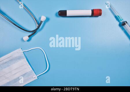 Idée conceptuelle de la médecine ou de l'industrie de la santé. Seringue, stéthoscope, tube sanguin et masque facial sur une surface bleue isolée Banque D'Images