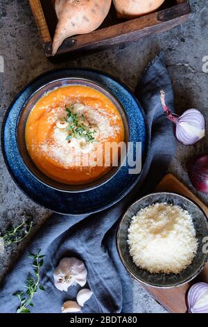 Soupe crémeuse aux pommes de terre douces, accompagnée de fromage Pecorino, de noix de cajou rôties et de thym frais dans un bol en céramique Banque D'Images