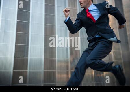 Homme d'affaires inconnu sautant à l'extérieur dans le flou de mouvement à travers le bâtiment urbain moderne de bureau arrière-plan Banque D'Images