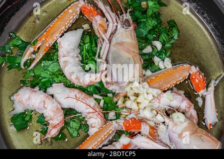 Fruits de mer frais langoustine vue de dessus closeup, préparé sur la poêle de cuisine. POV de langouste brute non cuite avec coquille, à cuire avec de l'huile, de l'ail et du persil. Banque D'Images