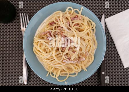 Des spaghettis carbonara servis sur une plaque bleue Banque D'Images