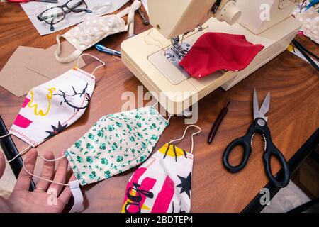 Une pile de masques cousus en tissu à motifs colorés. Les gens font des masques pour couvrir le manque de matériel de protection individuelle pour les hôpitaux. Banque D'Images