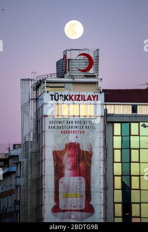 7 avril 2020 : la Supermoon éclaircit le ciel d'Istanbul le 7 avril 2020. Une superlune est une pleine lune qui coïncide presque avec la distance la plus proche que la Lune atteint à la Terre dans son orbite elliptique, ce qui entraîne une taille visible plus grande que d'habitude du disque lunaire, telle qu'elle est vue de la Terre. Bâtiment du Croissant-Rouge au premier plan, Kadikoy. Le Croissant-Rouge turc est la plus grande organisation humanitaire en Turquie et fait partie du Mouvement international de la Croix-Rouge et du Croissant-Rouge. Crédit: Tolga Ildun/ZUMA Wire/Alay Live News Banque D'Images