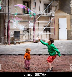 Deux enfants jouant avec des bulles dans une petite place à Barcelone. Banque D'Images